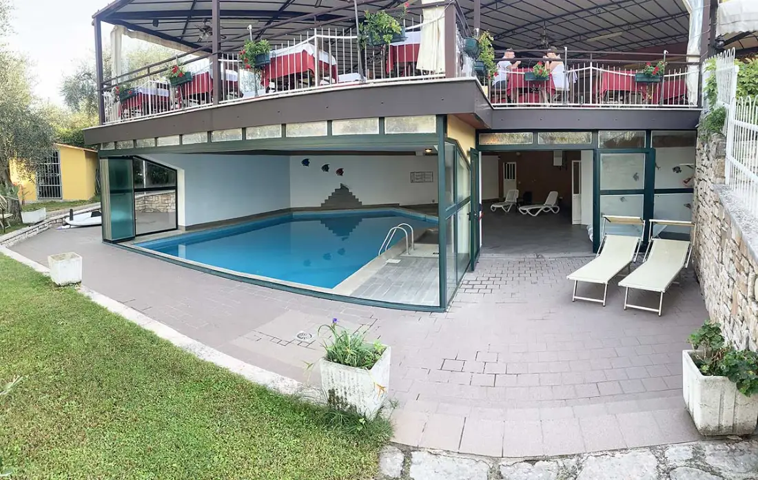 Piscina all'aperto dell'Hotel Rabay a Brenzone con vista sulla terrazza del ristorante e sul Lago di Garda.